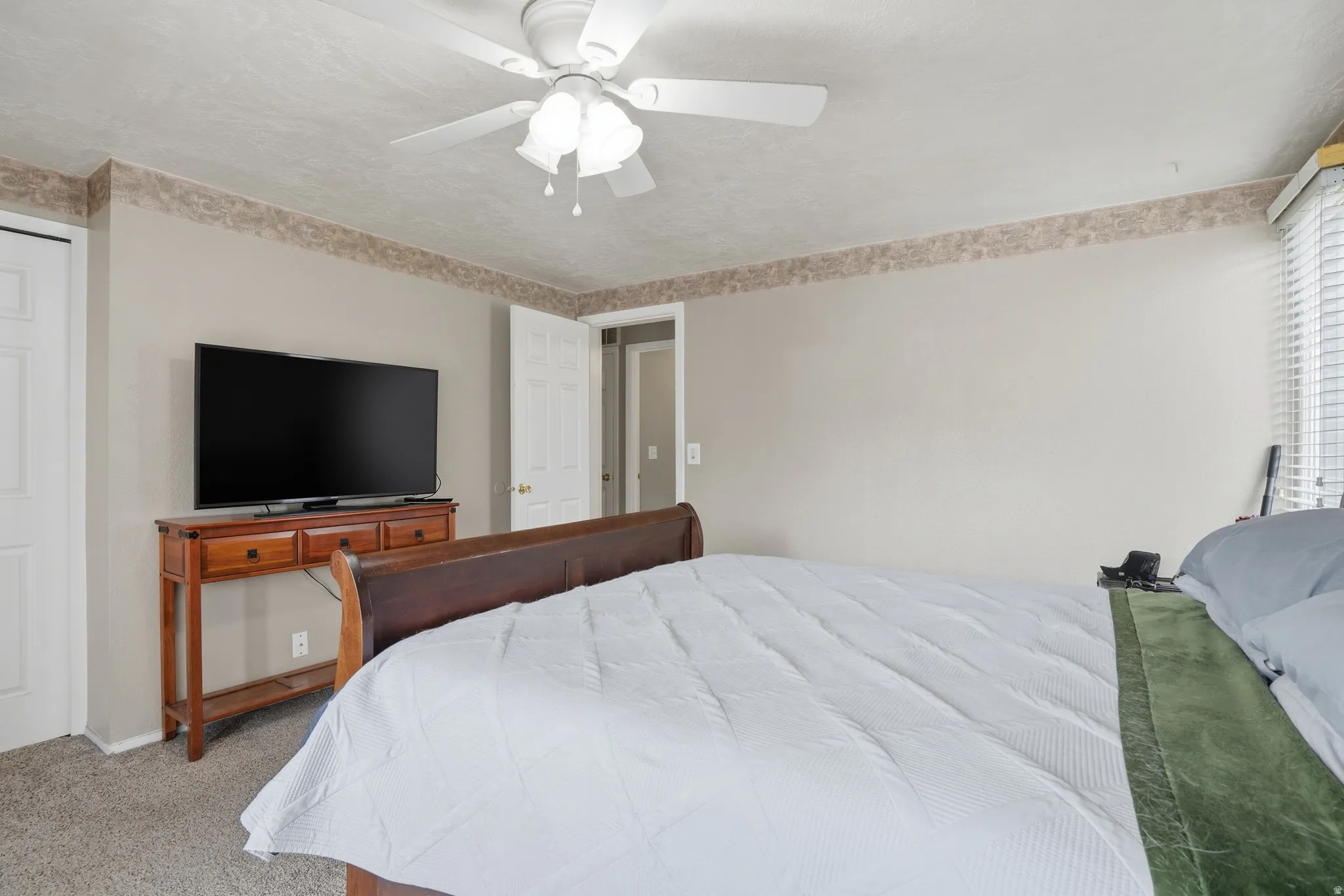 Carpeted bedroom featuring a ceiling fan and baseboards