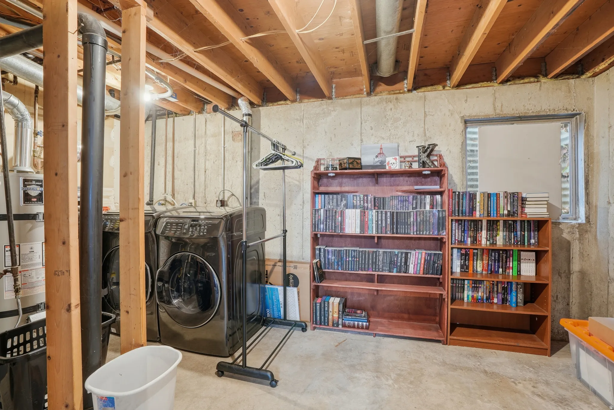 Unfinished basement featuring washer / clothes dryer and strapped water heater