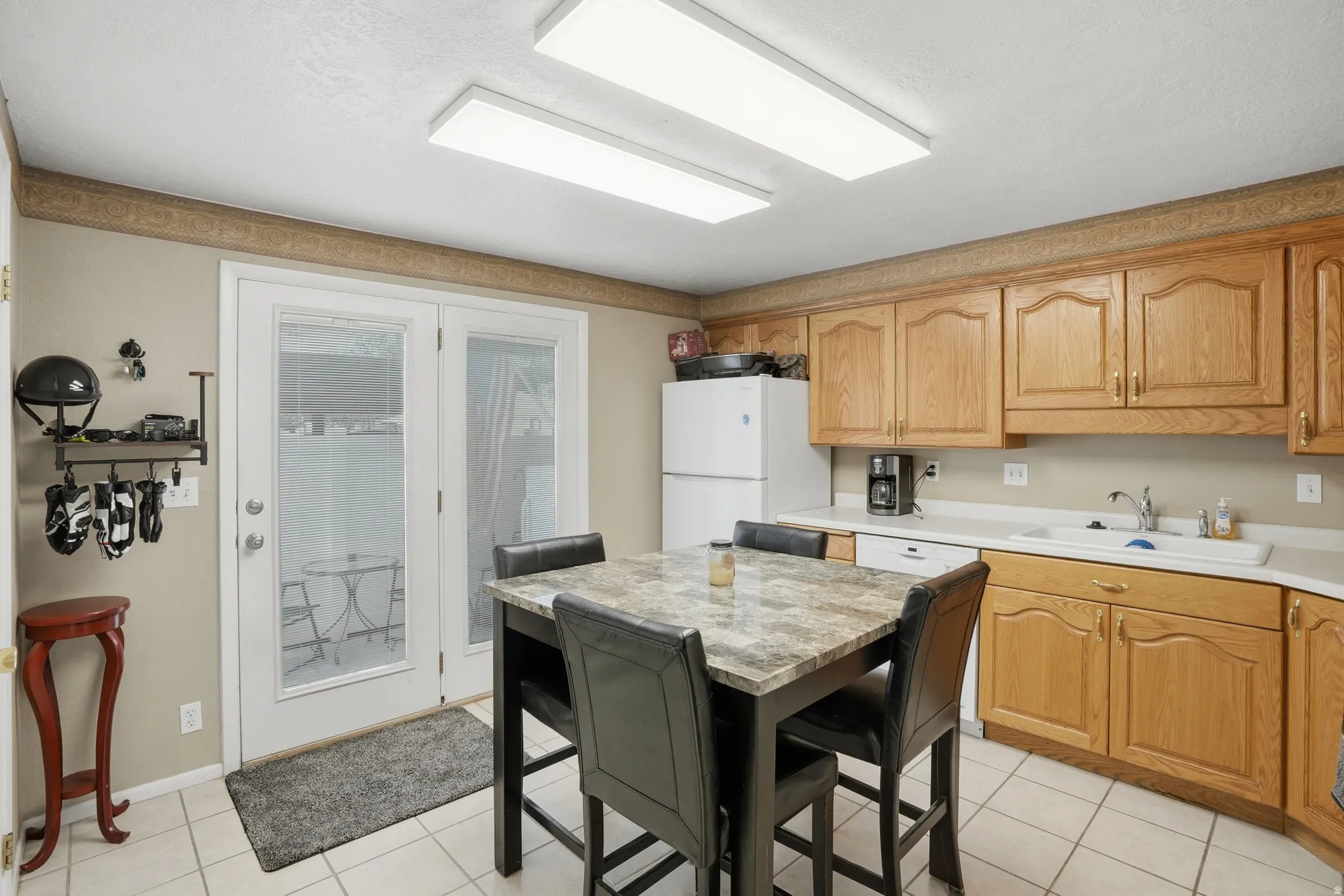 Kitchen with light countertops, white appliances, light tile patterned floors, and wood finish cabinetry