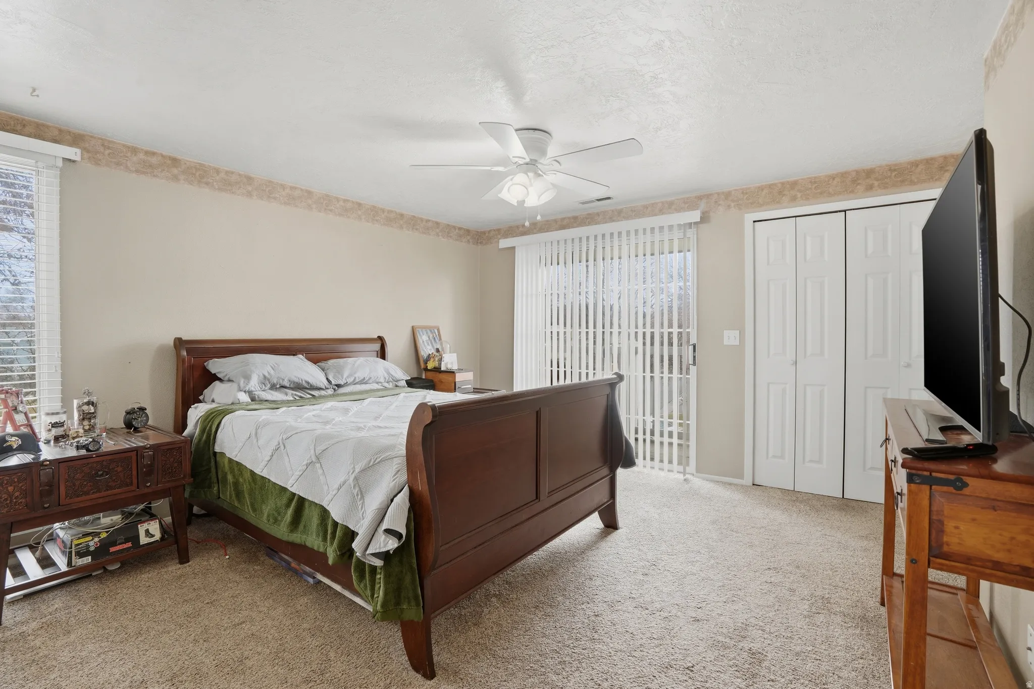 Bedroom with light colored carpet, a ceiling fan, access to exterior, and a textured ceiling