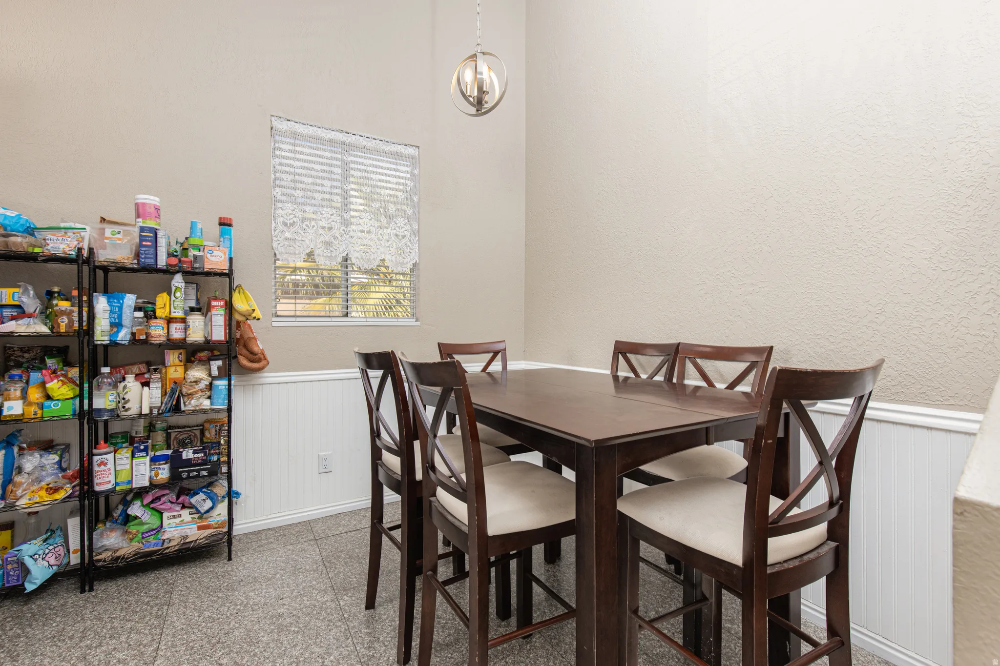 Dining space featuring a wainscoted wall and hanging lights