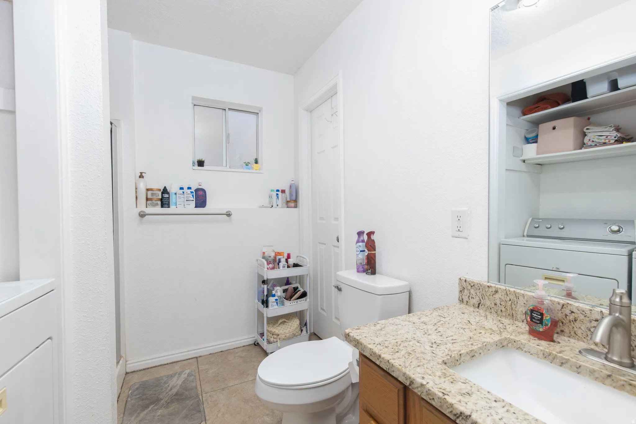 Full bath featuring vanity, washer / dryer, and light tile patterned flooring