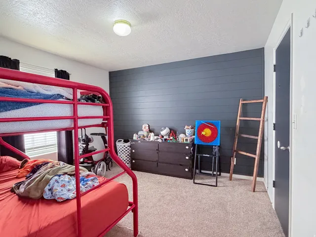 Neutral color palette with textured wall accent, recessed window, and wall-to-wall carpeting