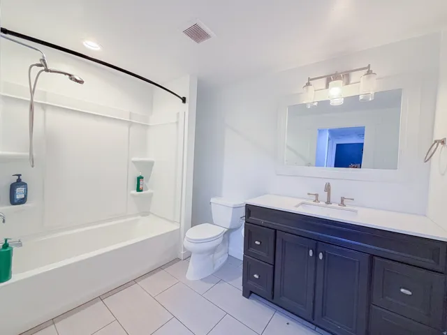 Vanity with dark wood-finish cabinetry, white countertop, and brushed nickel hardware