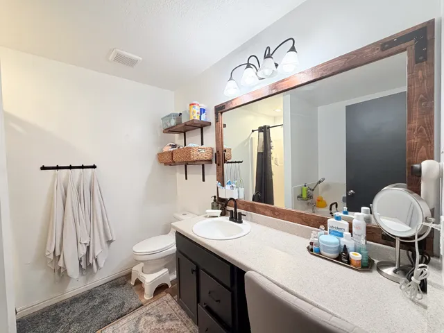 Vanity with a single basin sink, wood-framed mirror, and attached sconce lighting