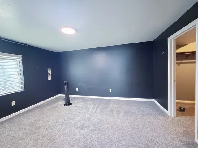Wall-to-wall carpeting, recessed ceiling light fixture, window with horizontal blinds, and a built-in closet with shelving and hanging rod