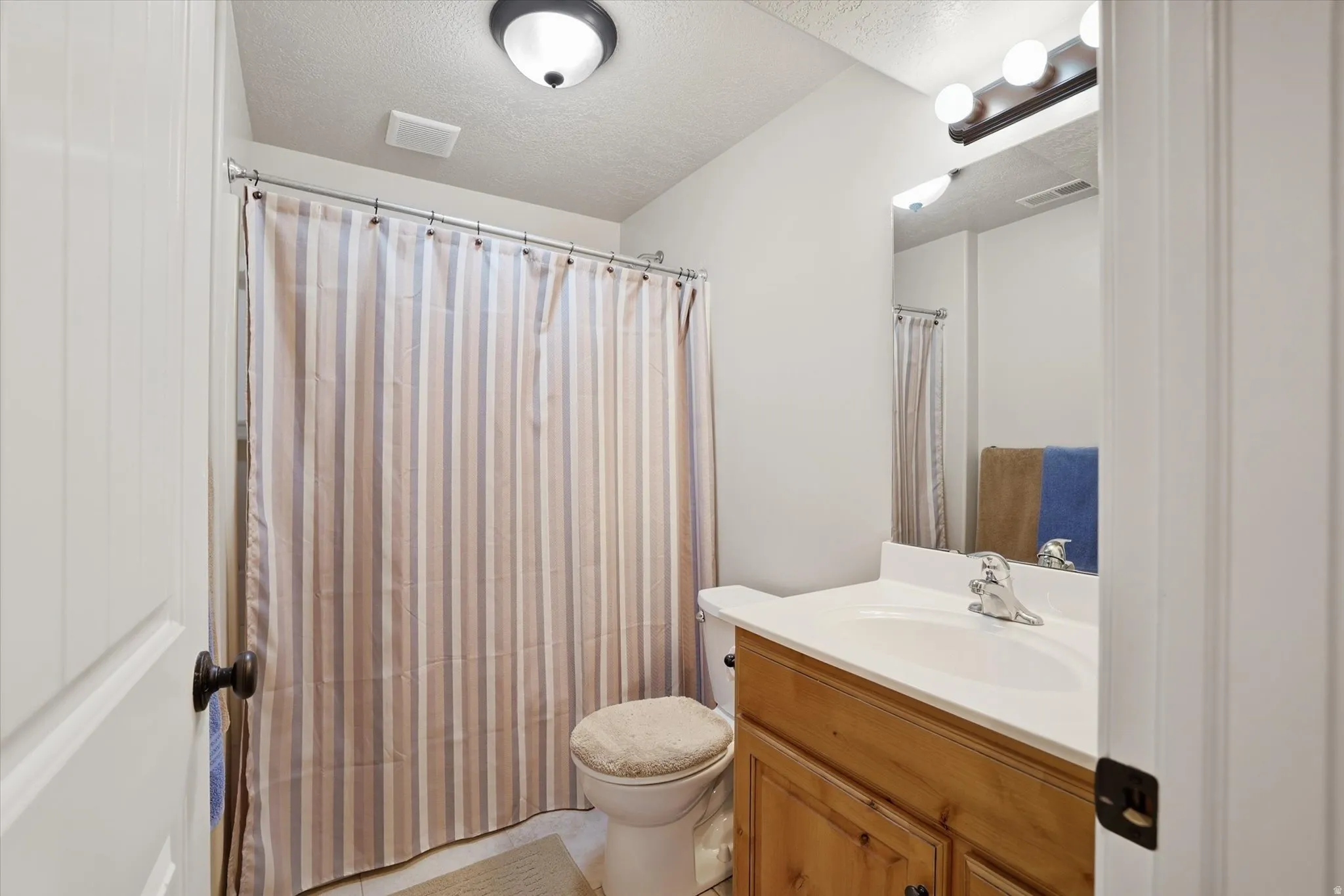 Full bath with vanity, a textured ceiling, and a shower with shower curtain