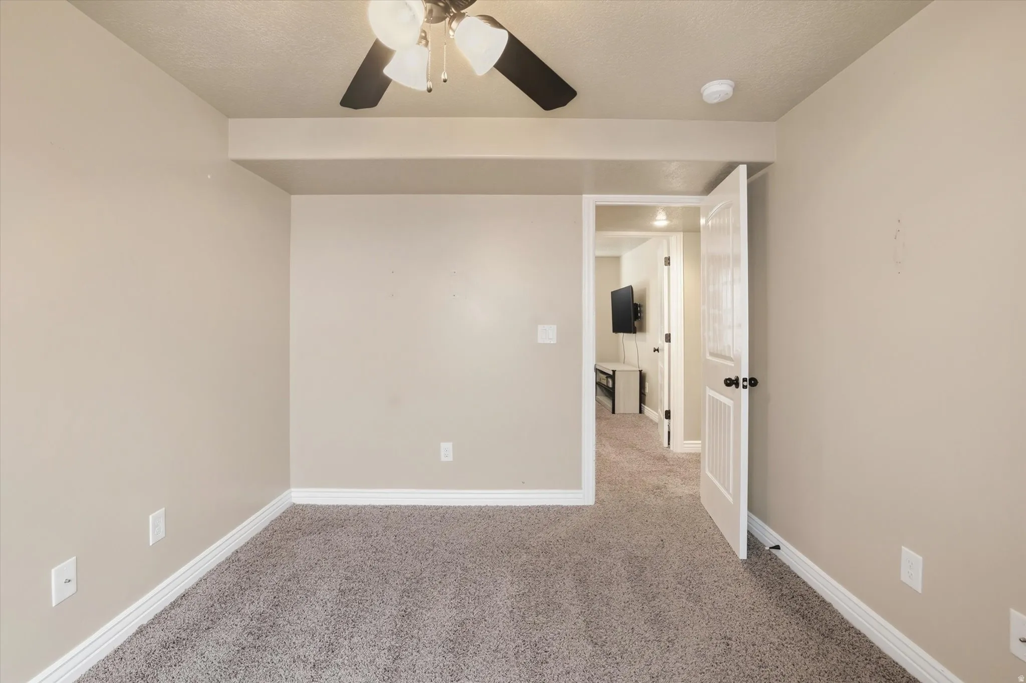 Carpeted spare room with ceiling fan and baseboards