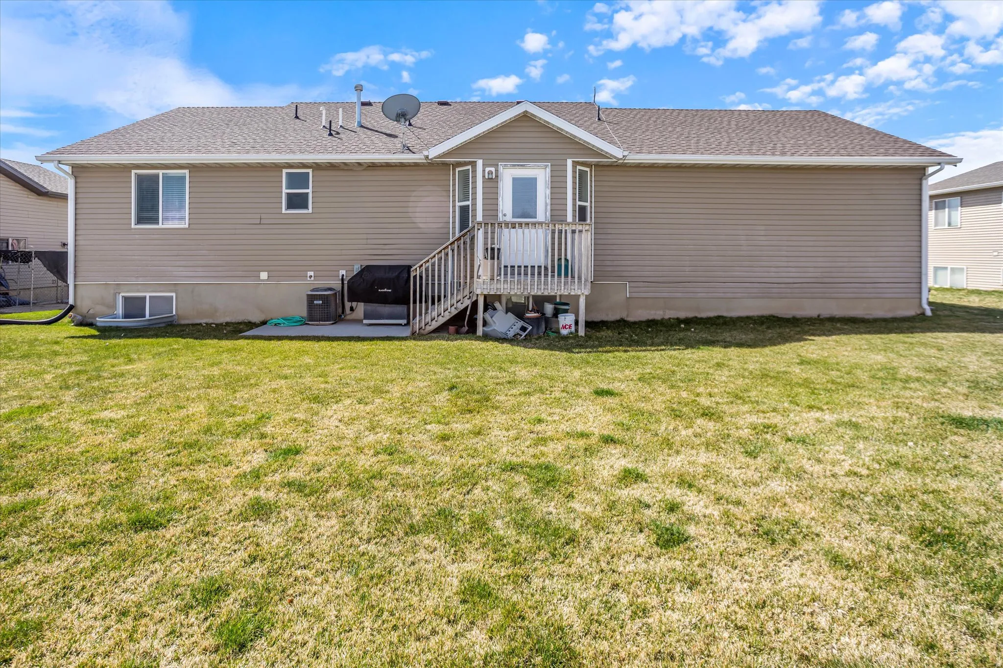 Back of property featuring a wooden deck, a lawn, and roof with shingles