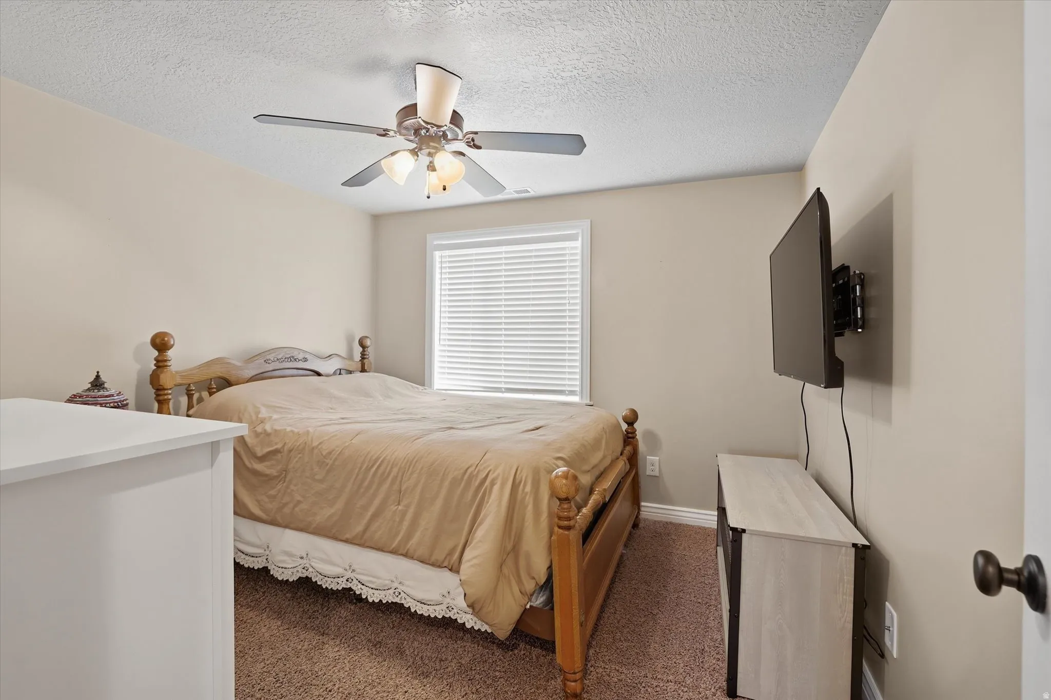 Carpeted bedroom with a ceiling fan and a textured ceiling