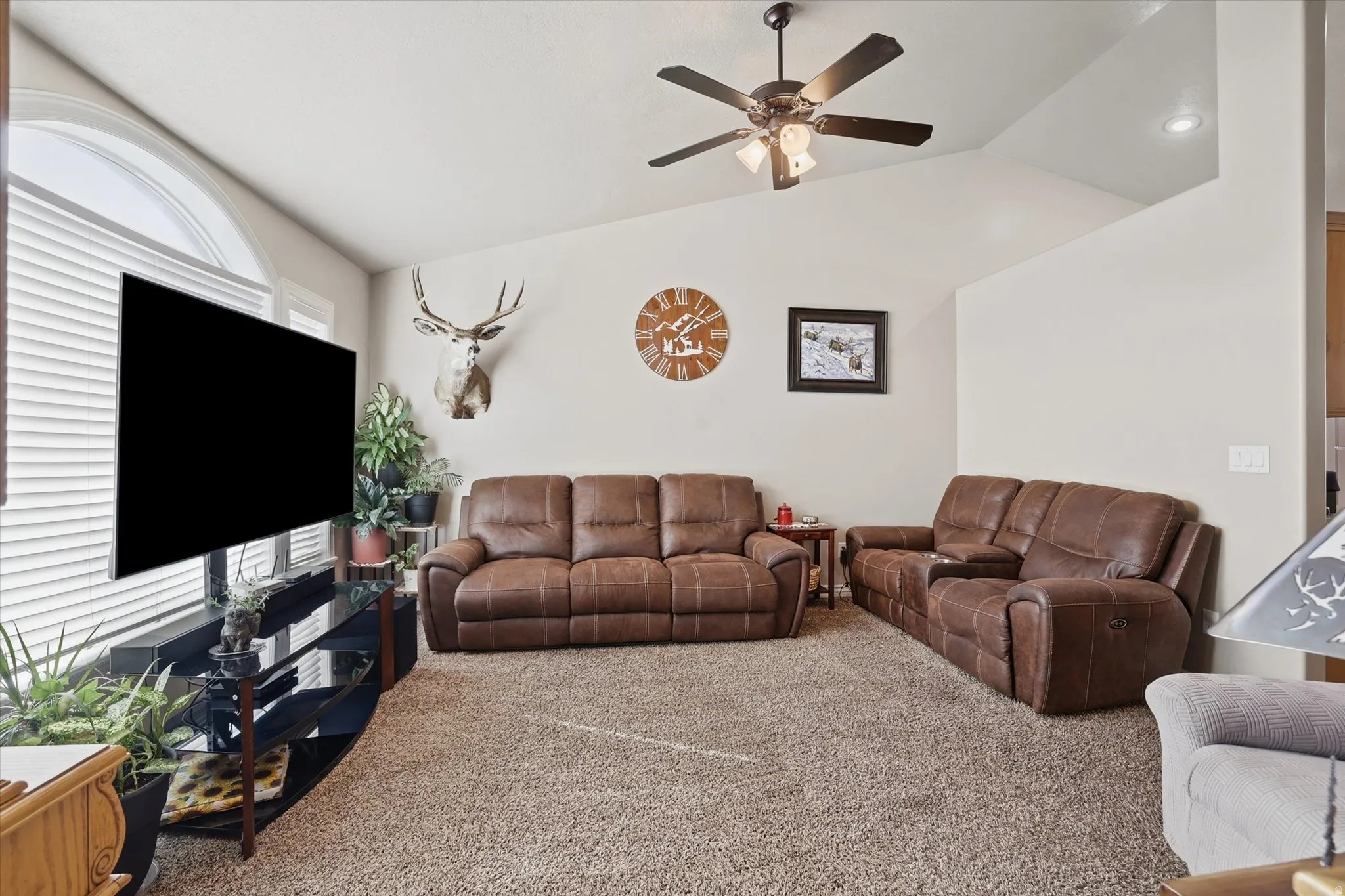 Carpeted living room with a ceiling fan, vaulted ceiling, and plenty of natural light