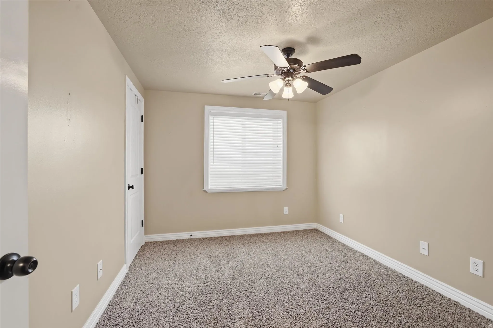 Unfurnished room with light carpet, a textured ceiling, and a ceiling fan