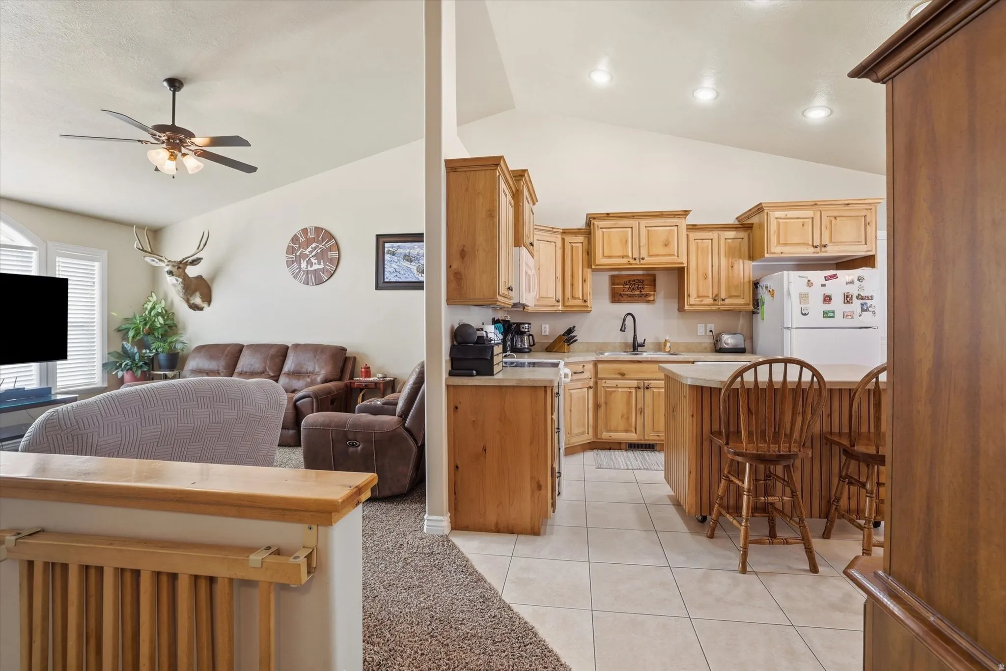 Kitchen with open floor plan, light countertops, a breakfast bar area, lofted ceiling, and white appliances