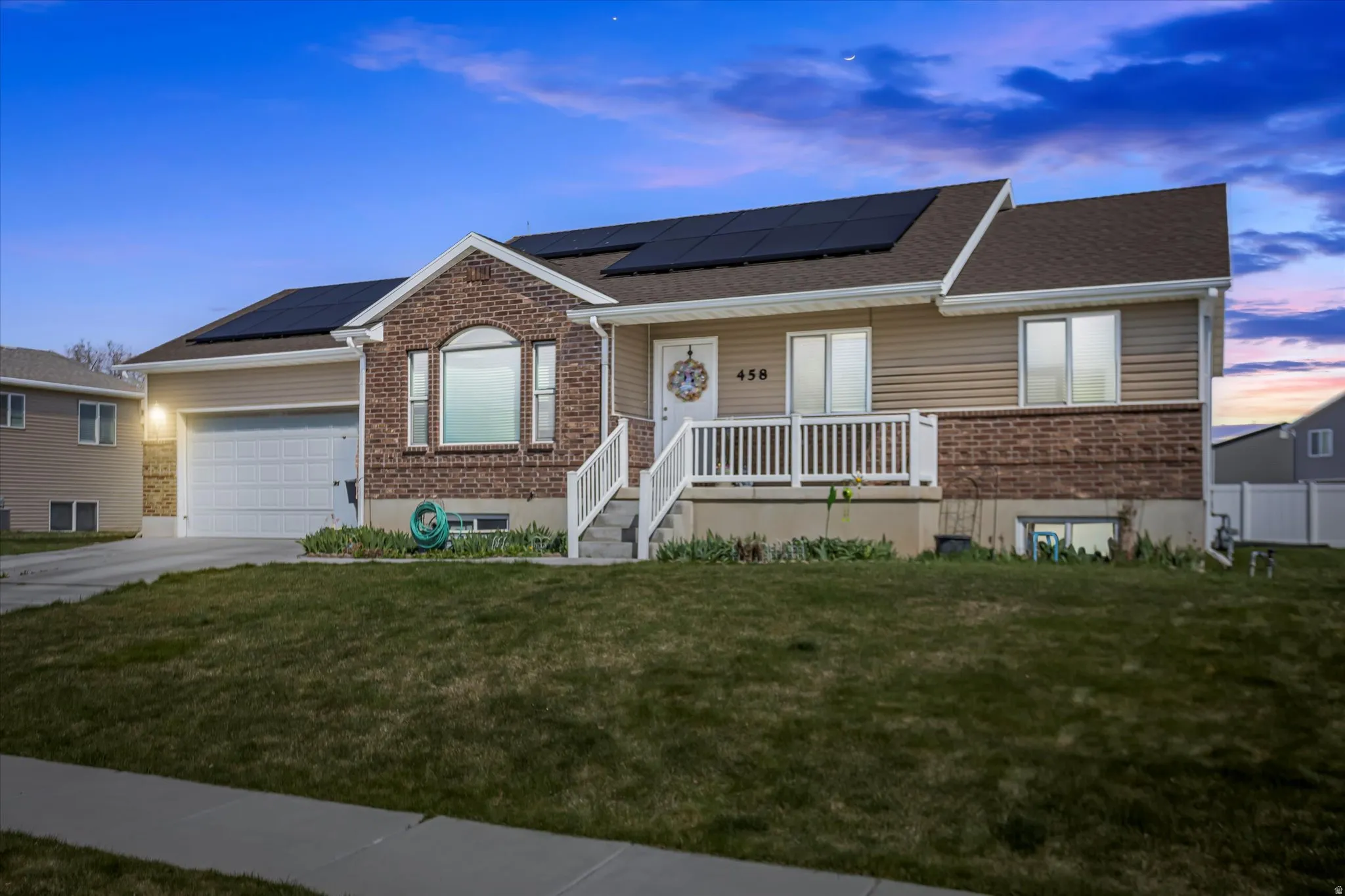 Ranch-style house with roof mounted solar panels, a porch, brick siding, and a front lawn