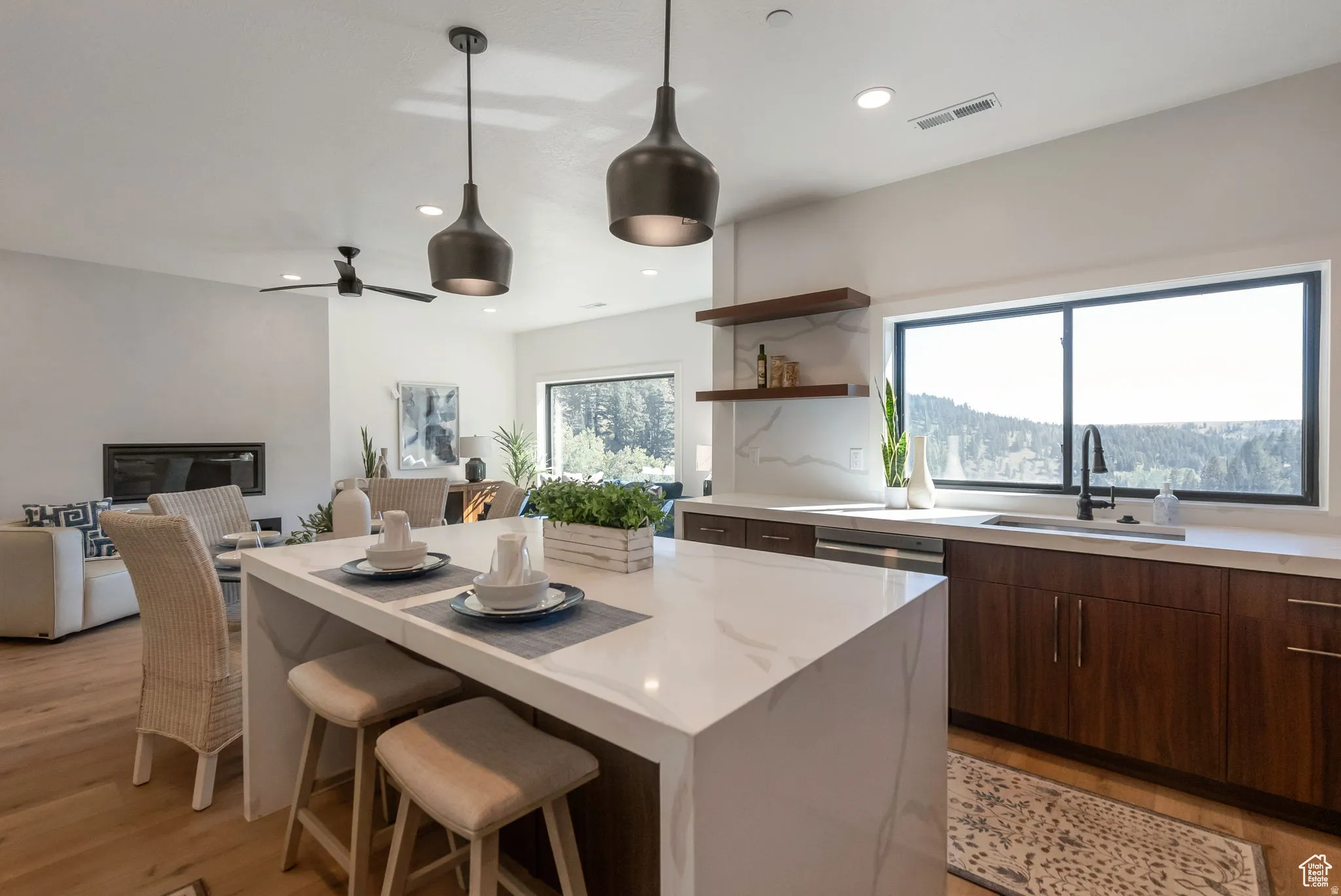 Kitchen featuring a breakfast bar area, open floor plan, light stone counters, open shelves, and dark wood finish cabinets