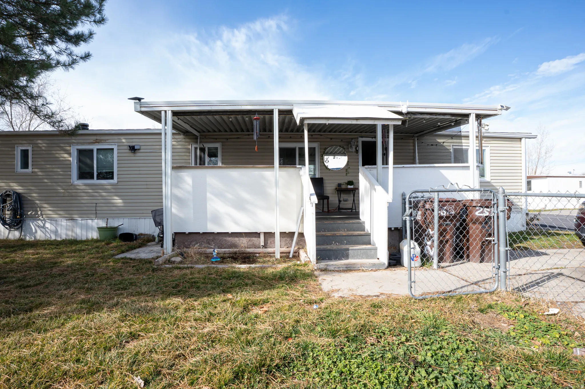 Manufactured / mobile home featuring a gate, a front yard, and covered porch