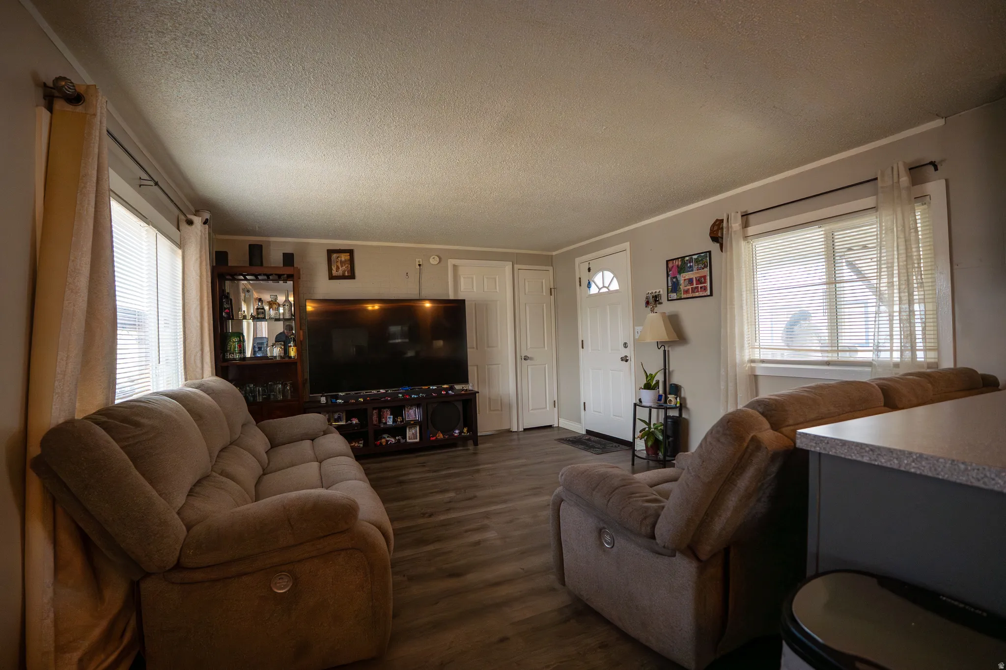 Living room featuring dark wood-style flooring, a textured ceiling, and ornamental molding