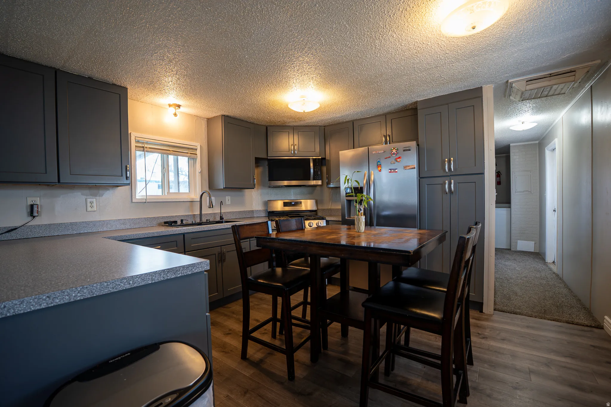 Kitchen with gray cabinetry, stainless steel appliances, a textured ceiling, dark wood finished floors, and cooling unit