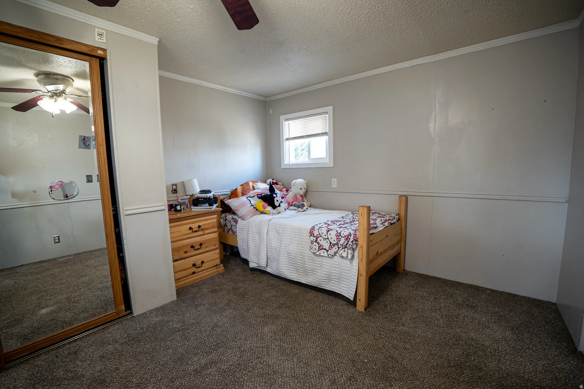 Bedroom featuring carpet floors, a textured ceiling, crown molding, and ceiling fan