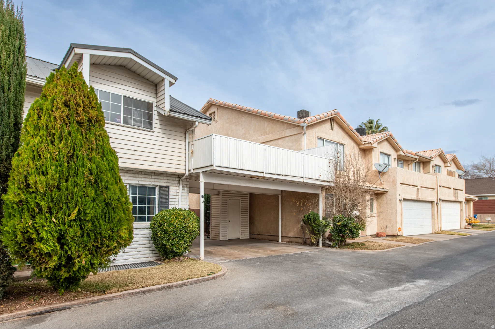 View of front of house featuring asphalt driveway, a carport, and a balcony