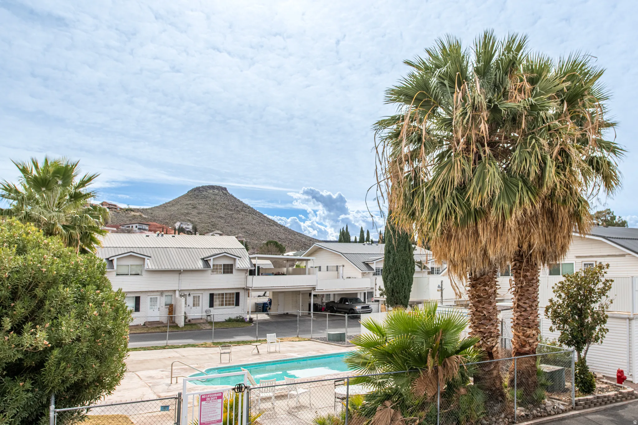 View of swimming pool with a mountain view, a gate, and a residential view