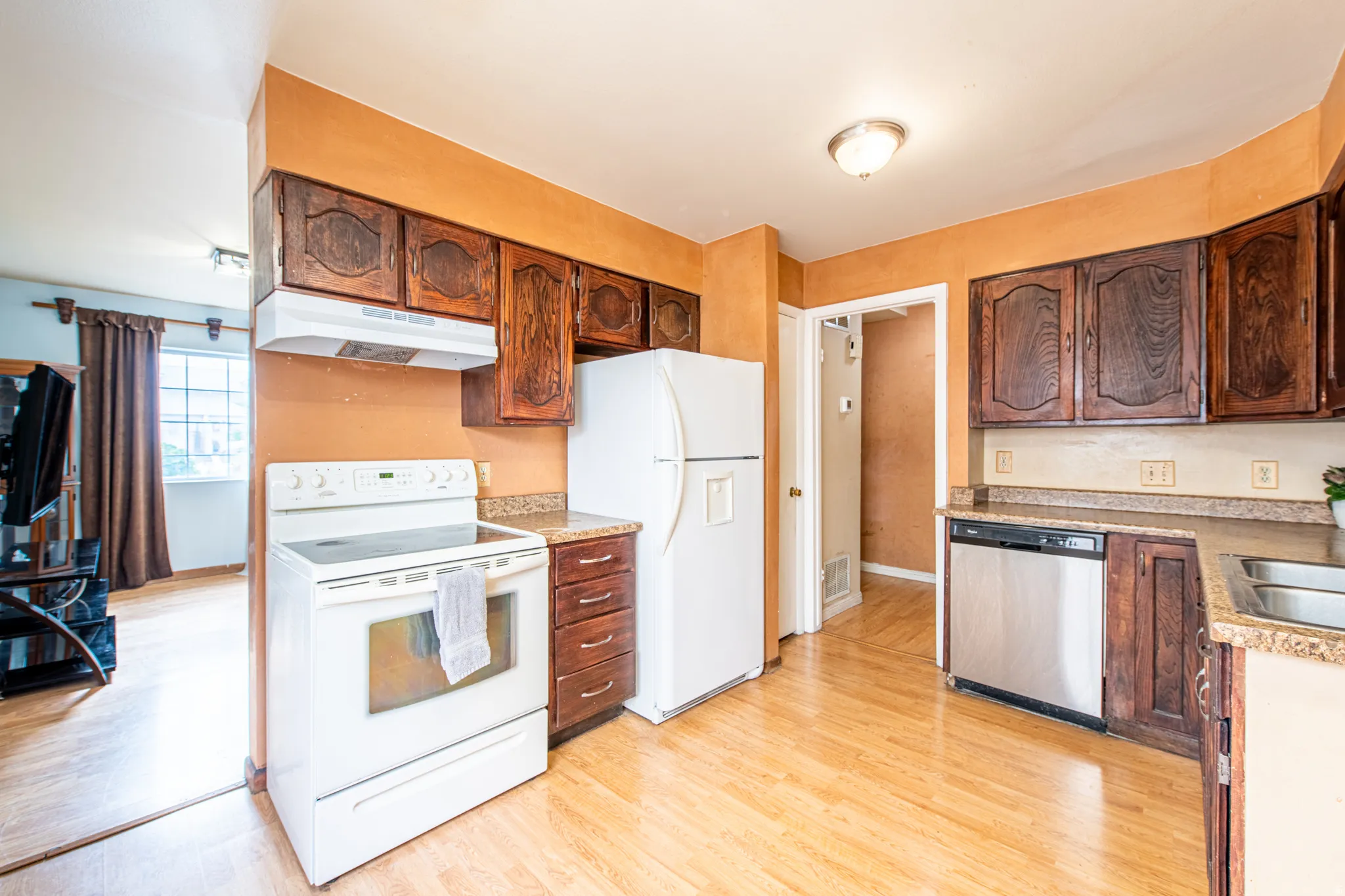 Kitchen with white appliances, light wood-style floors, and light countertops