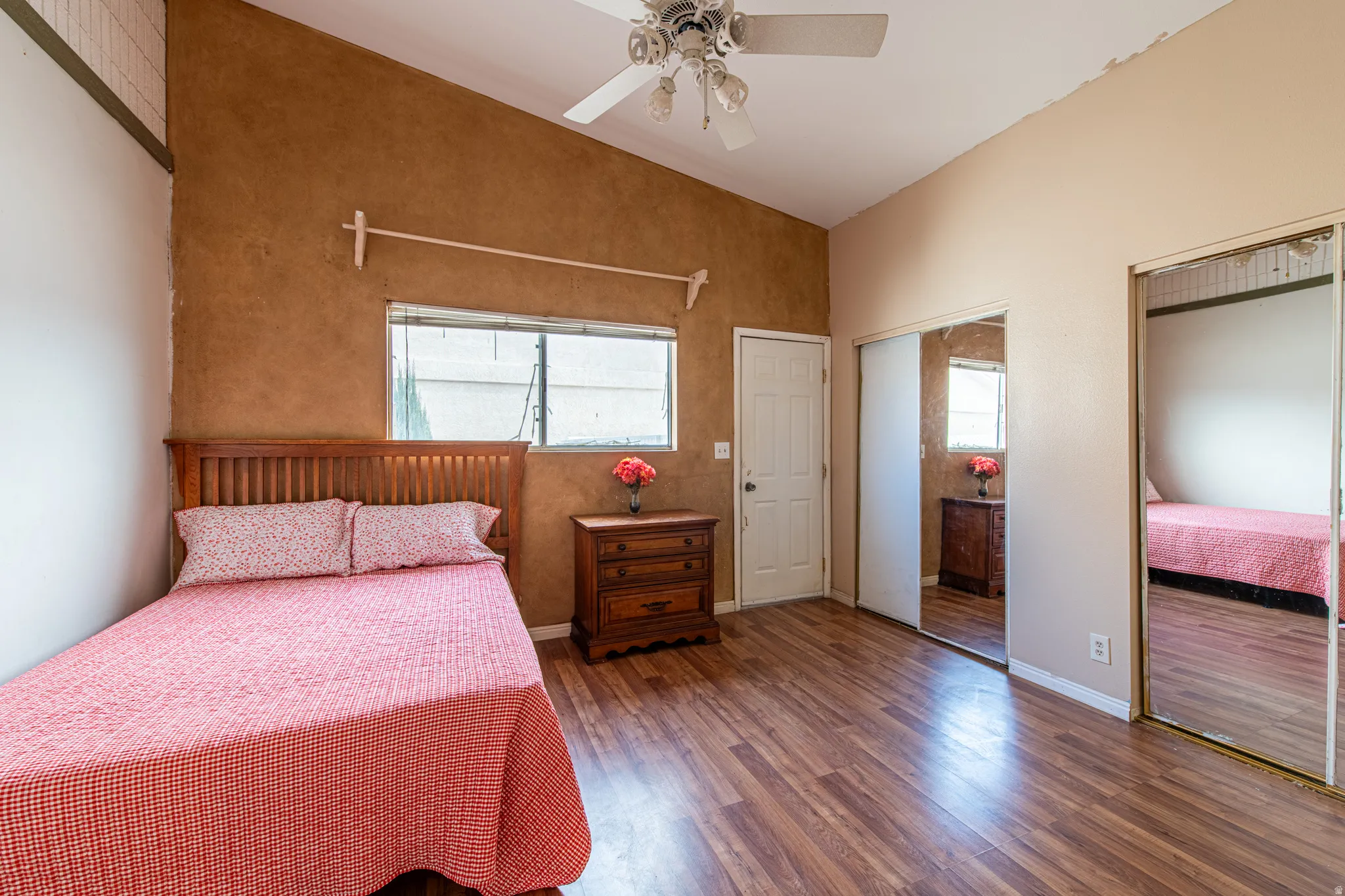 Bedroom featuring lofted ceiling, multiple closets, wood finished floors, and ceiling fan