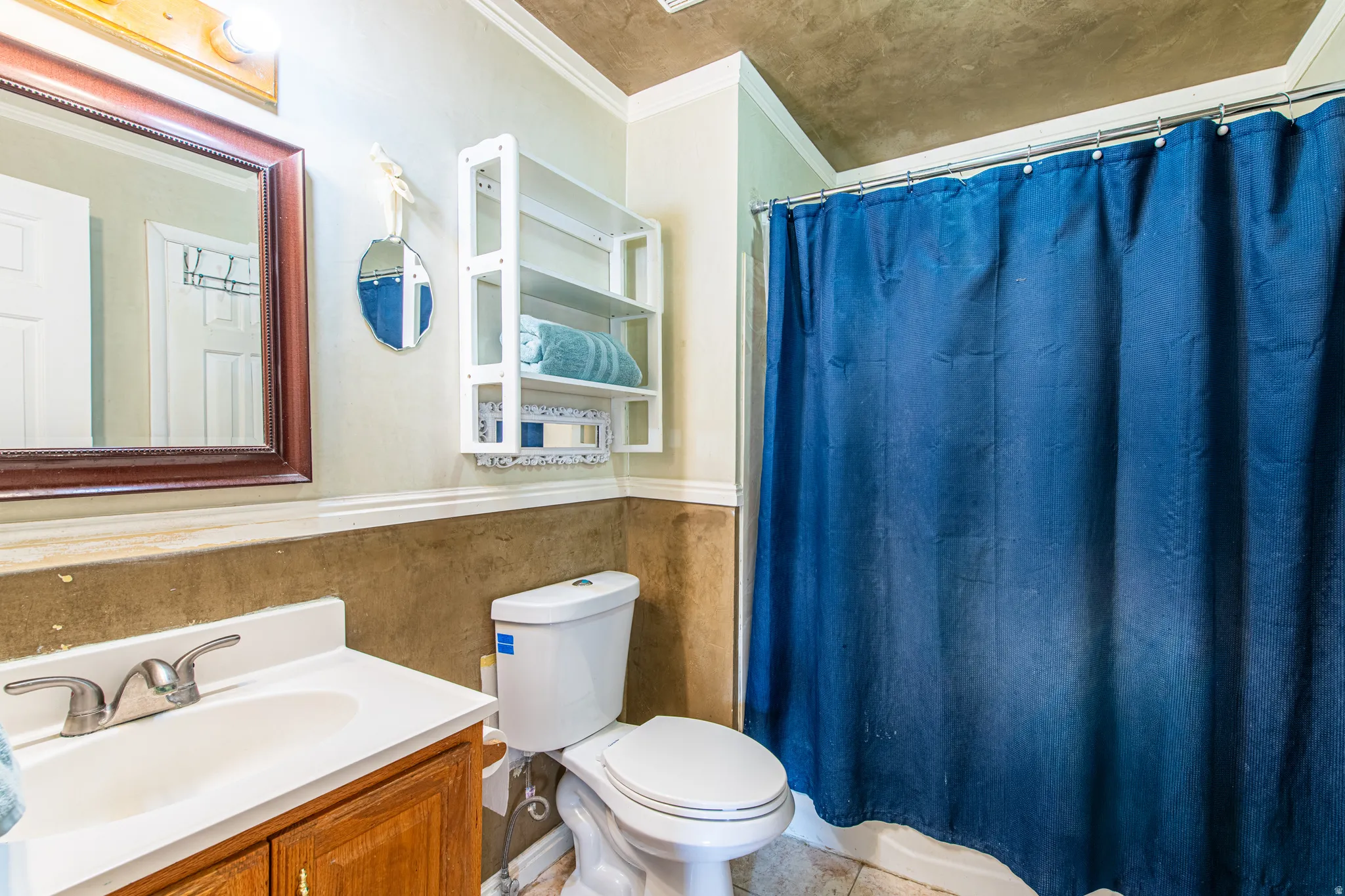 Full bathroom with vanity, ornamental molding, and a wainscoted wall