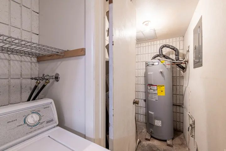 Laundry area with washer / dryer, electric water heater, concrete flooring, and electric panel