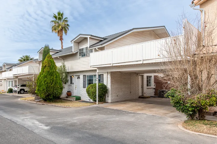 View of front of property featuring a balcony and asphalt driveway