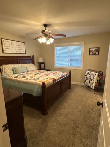 Carpeted bedroom featuring a textured ceiling and a ceiling fan
