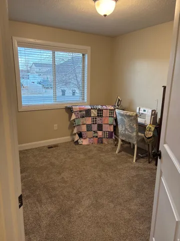 Carpeted office space featuring a textured ceiling and baseboards
