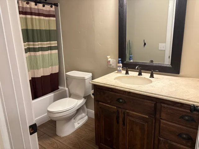 Full bath with vanity, dark wood-type flooring, and shower / bath combo with shower curtain