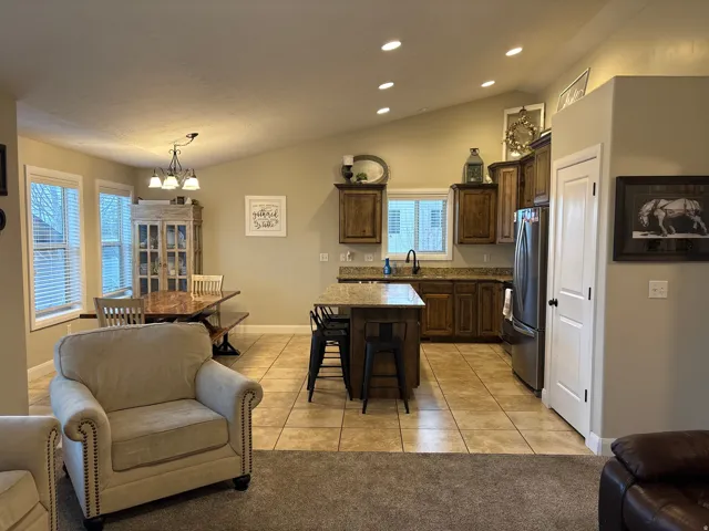 Kitchen with dark wood finish cabinetry, light tile patterned floors, a breakfast bar, lofted ceiling, and a center island