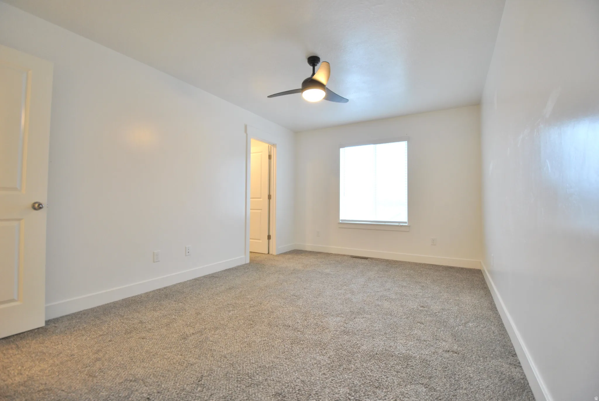Primary Bedroom with light colored carpet and a ceiling fan
