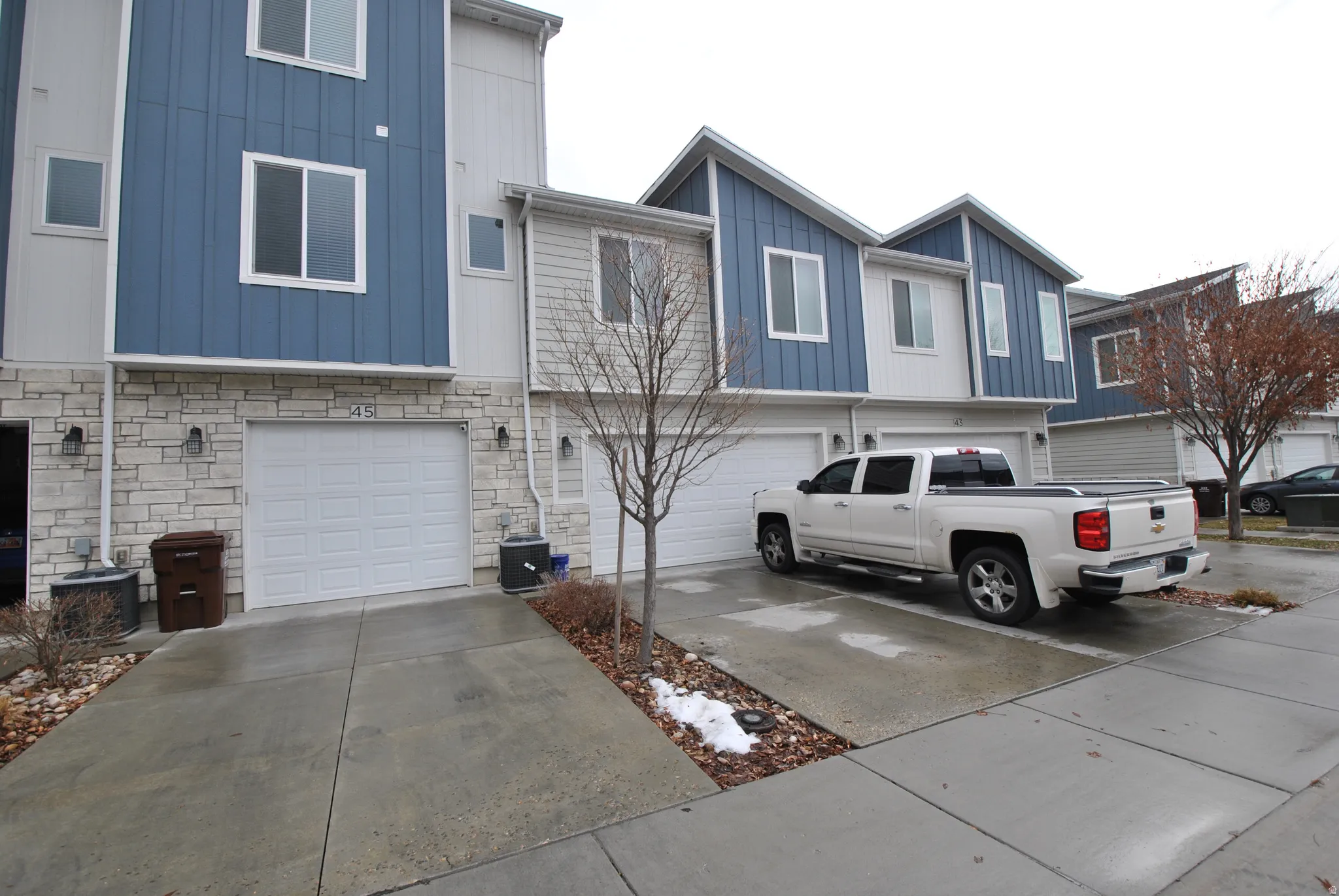 View of front of home featuring board and batten siding, stone siding, an attached garage, and concrete driveway