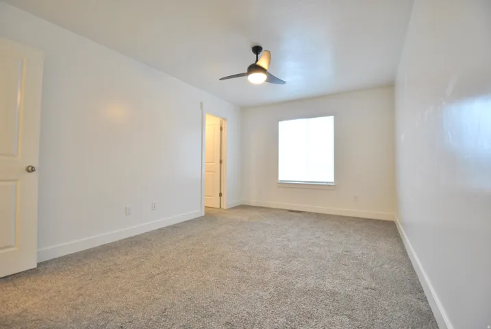 Primary Bedroom with light colored carpet and a ceiling fan