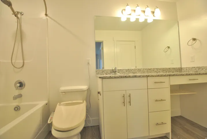 Primary full bath featuring vanity, shower / washtub combination, and dark wood-type flooring
