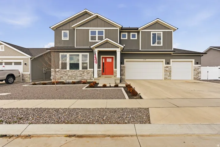Craftsman inspired home featuring stone siding, driveway, and an attached garage