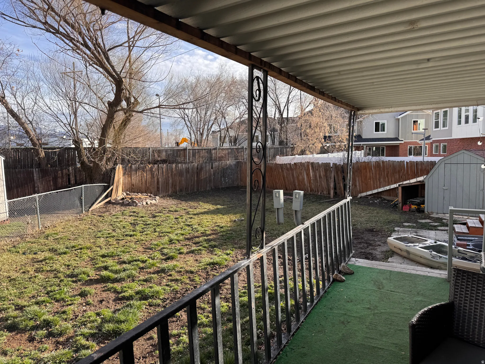 Fenced backyard with a storage unit and a patio area
