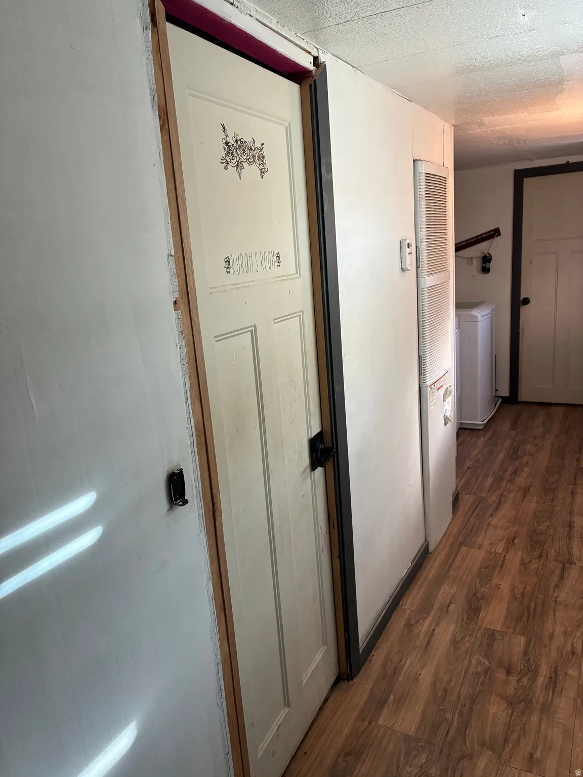 Hall with dark wood-style floors, washer / clothes dryer, a heating unit, and a textured ceiling