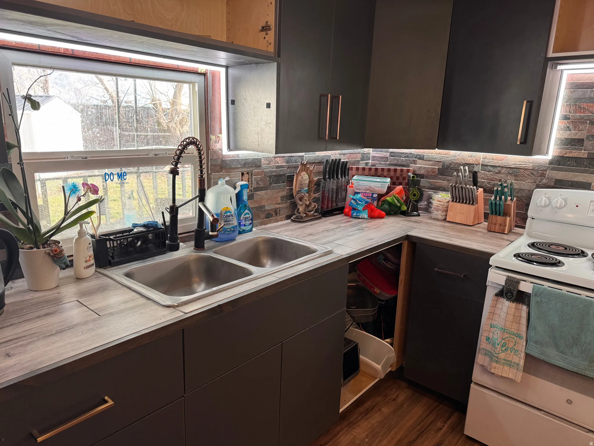 Kitchen with white electric range, light countertops, dark wood finish cabinetry, dark wood-style flooring, and modern cabinets