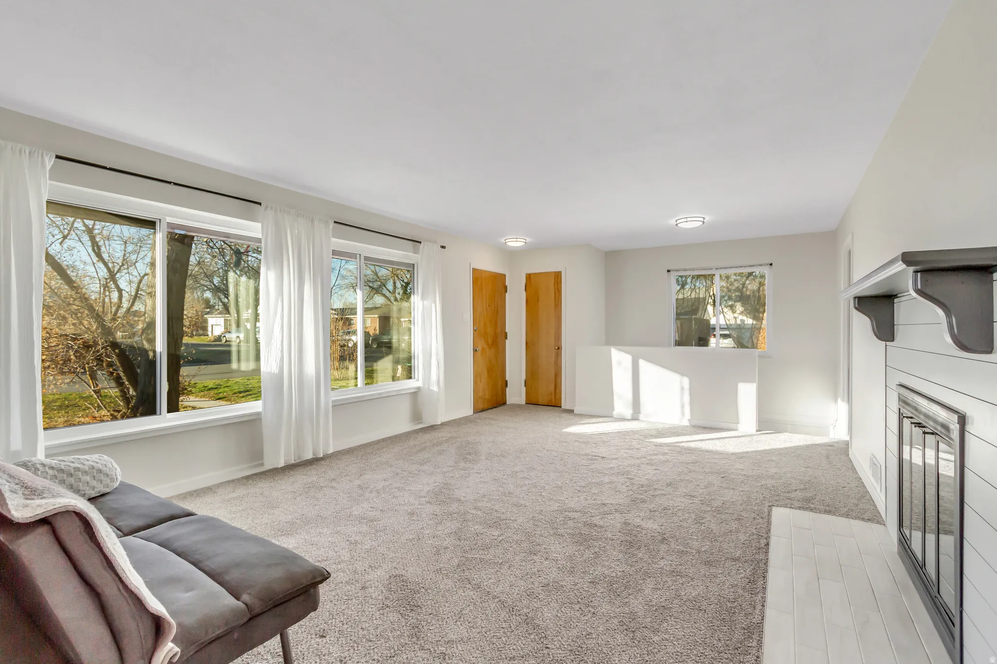 Unfurnished living room with light colored carpet and a glass covered fireplace
