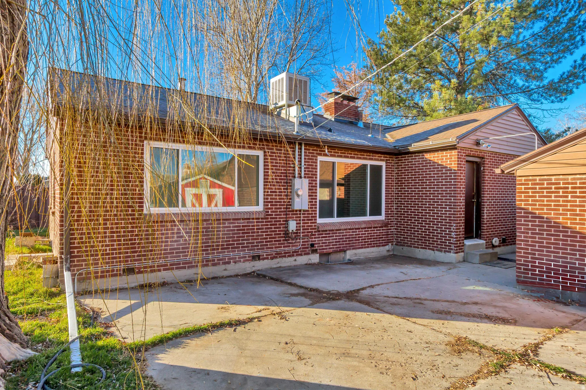 Back of house with brick siding, a chimney, and a patio