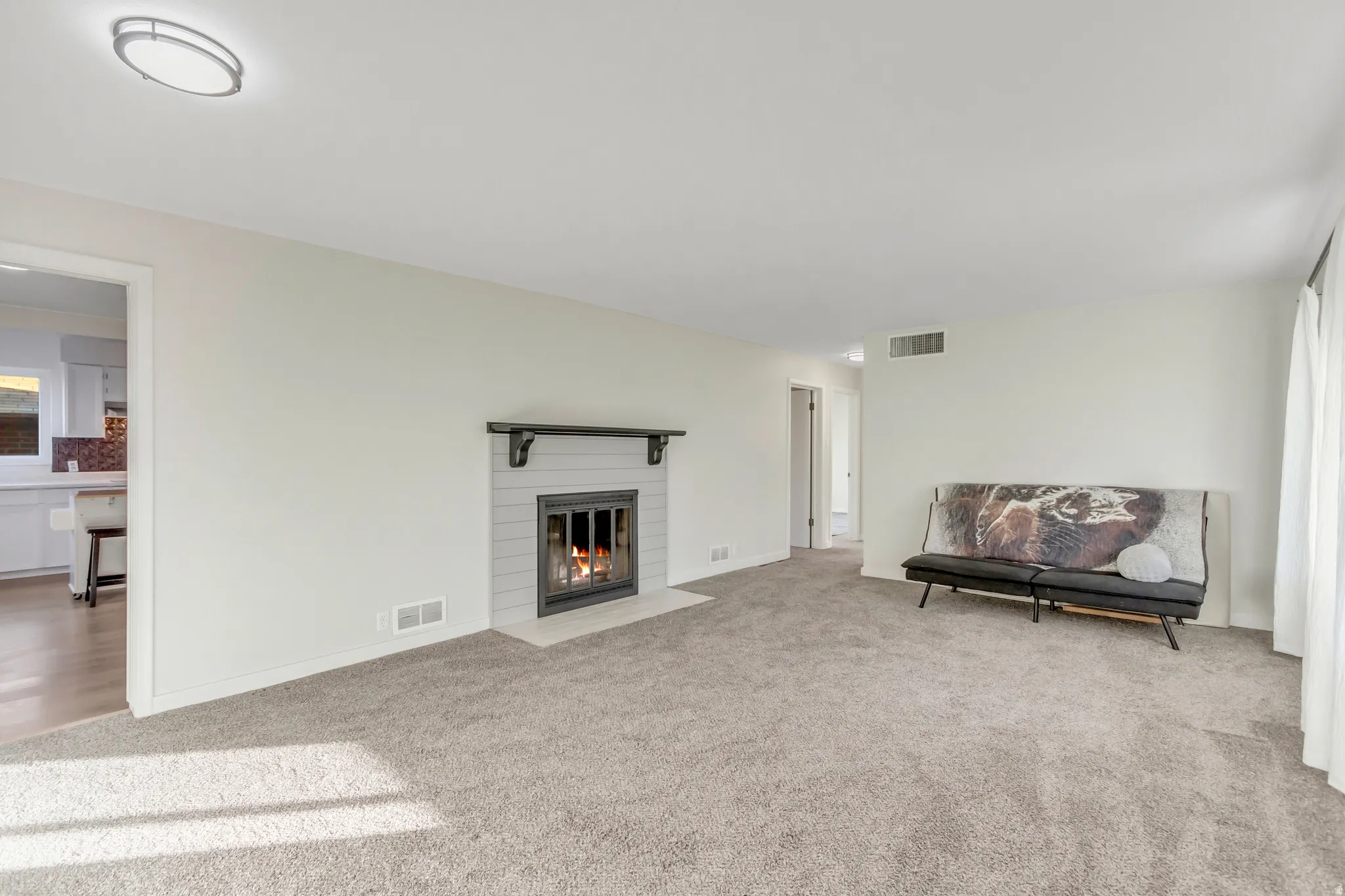 Living room with light colored carpet and a fireplace with flush hearth