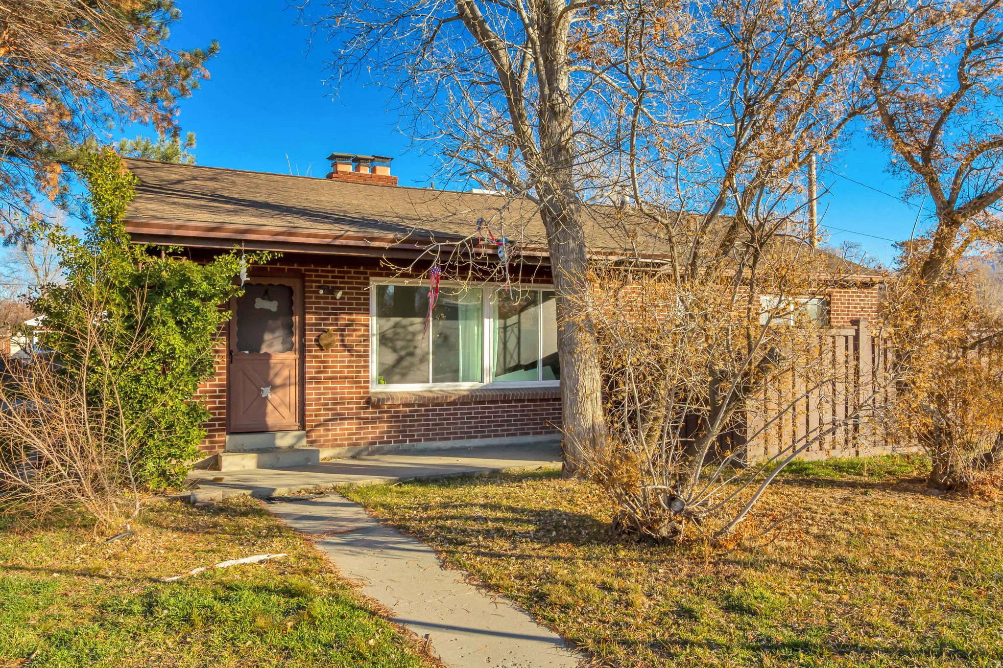 Bungalow featuring brick siding, a chimney, roof with shingles, and a front lawn