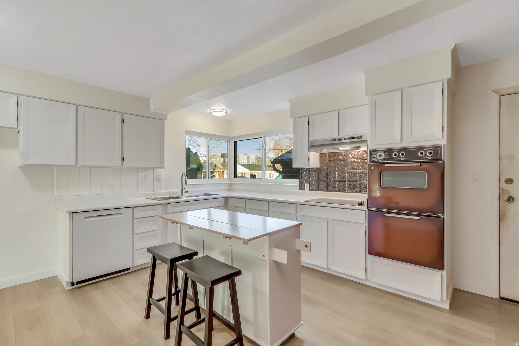Kitchen featuring a kitchen bar, white cabinets, dishwasher, and light wood-type flooring