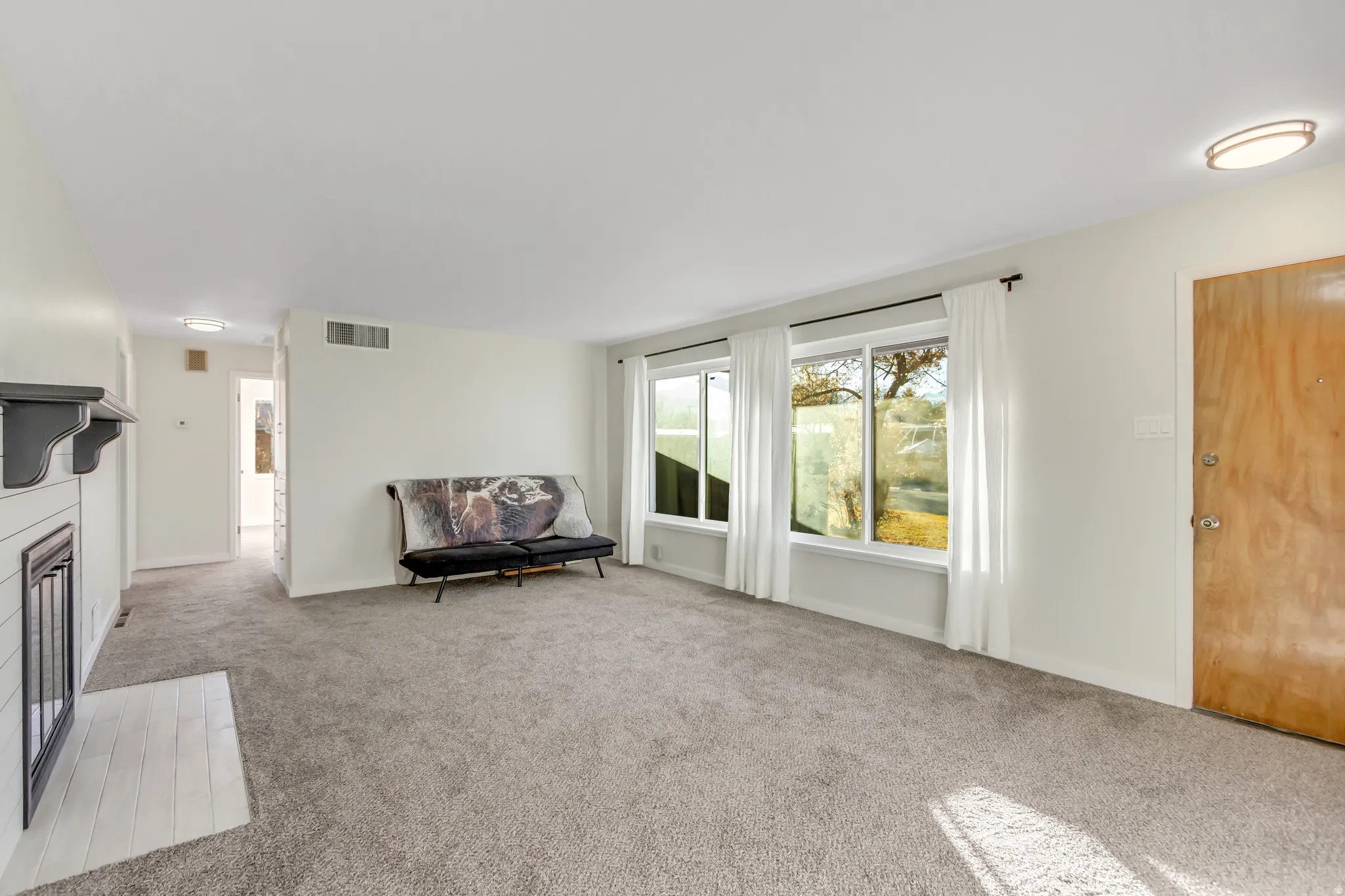 Living area featuring a fireplace with flush hearth and carpet