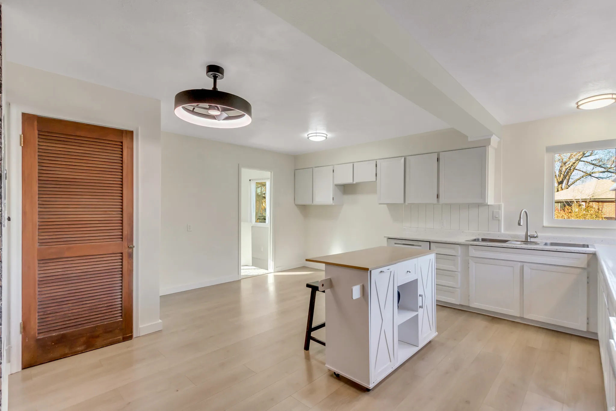 Kitchen with a breakfast bar, white cabinetry, light wood-style floors, and a center island
