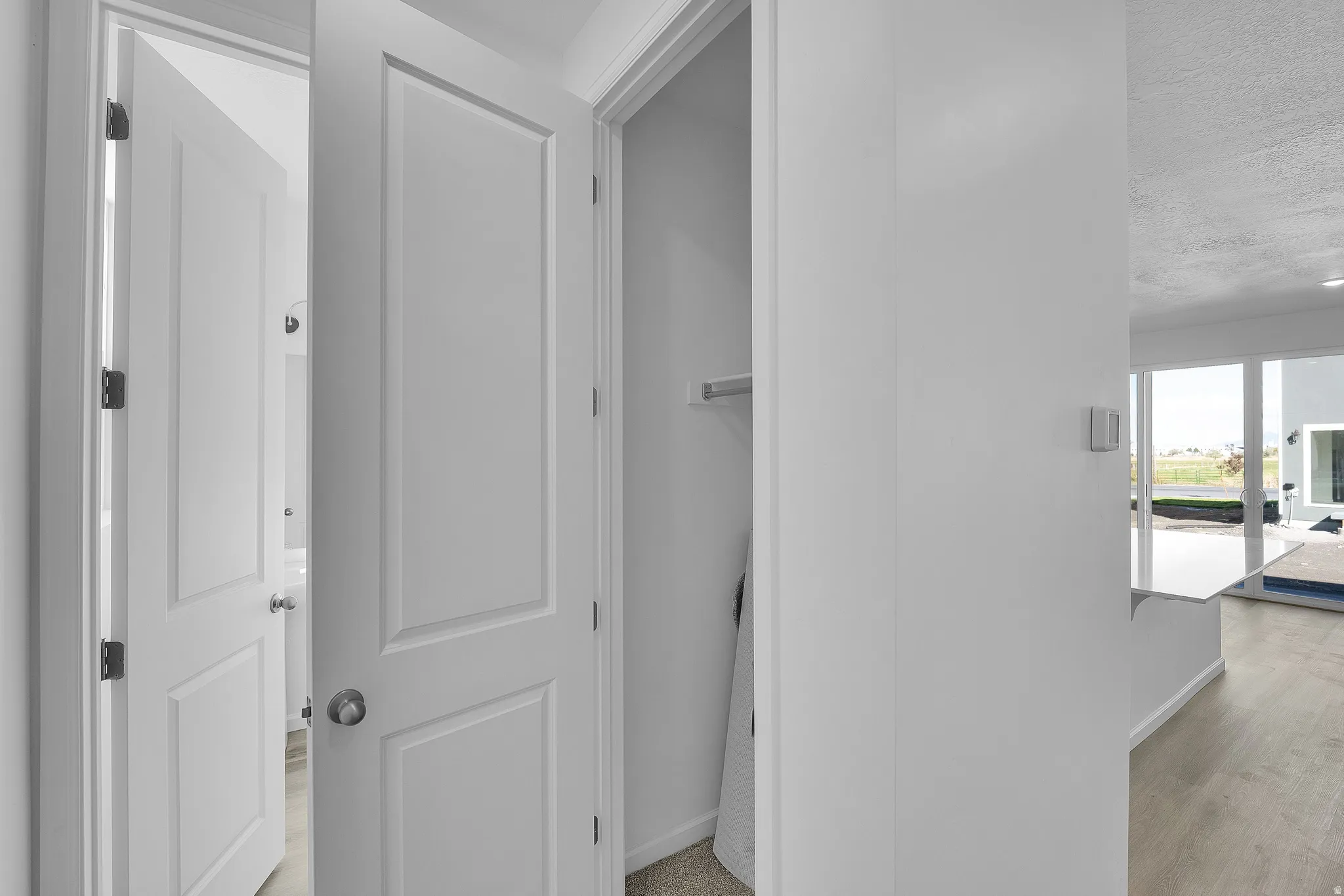 Hallway featuring a textured ceiling and light wood-style floors